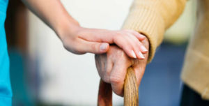 cuidadora cogiendo la mano a un anciano