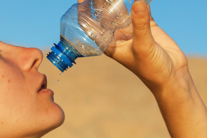 Chica intentando beber agua de una botella
